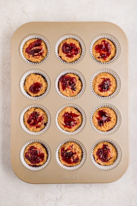 Layered Peanut Butter and Jelly Muffins in a tin to bake.