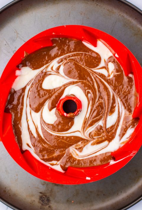 Cake batter being spread in a cake pan.