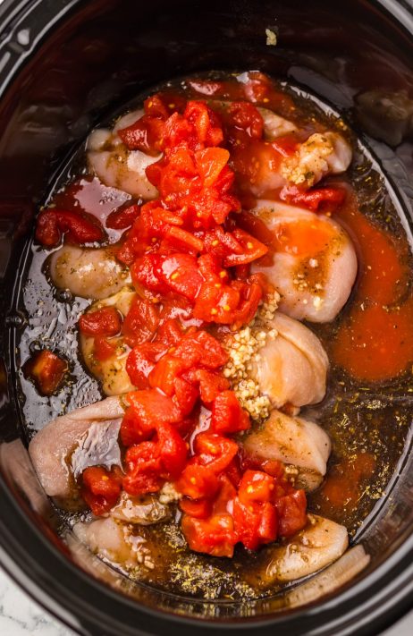Slow Cooker full of all the ingredients for an uncooked Bruschetta Chicken.