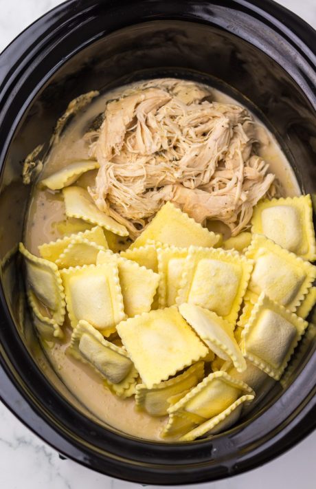 Frozen ravioli being added to a Slow Cooker.