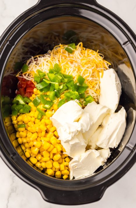 A Slow Cooker with sausage, cream cheese, diced tomatoes with green chiles, corn, chopped jalapeños, Monterey Jack cheese, garlic powder, onion powder, smoked paprika, salt, and pepper.