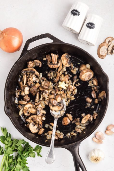 A spoon stirring cooked ingredients in a cast iron skillet.
