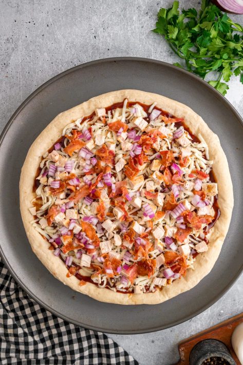 Unbaked BBQ Chicken pizza wiht toppings.