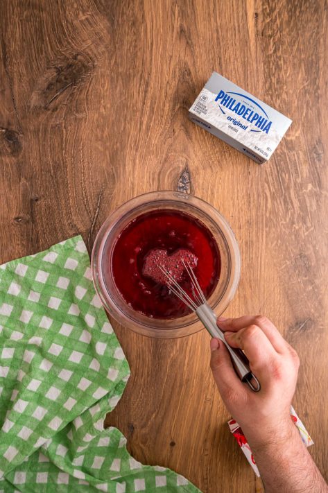 Cherry Jell-O being whisked in a bowl.