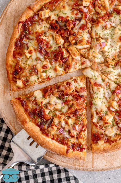 A cut BBQ Chicken Pizza on a pizza stone.