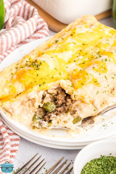 A plate of a few Creamy Beef Enchiladas with a few bites missing.