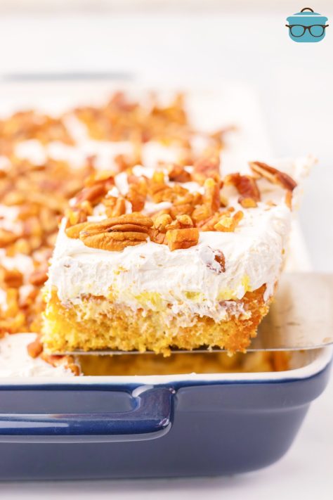 A slice of Hummingbird Poke Cake being removed from the cake dish.