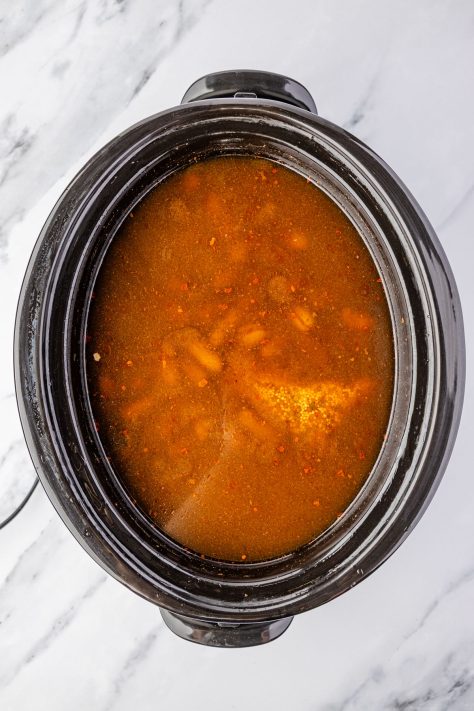 Slow Cooker with peanuts and spices submerged in water.