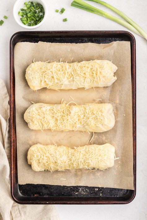 Unbaked chicken bakes with egg wash and cheese.