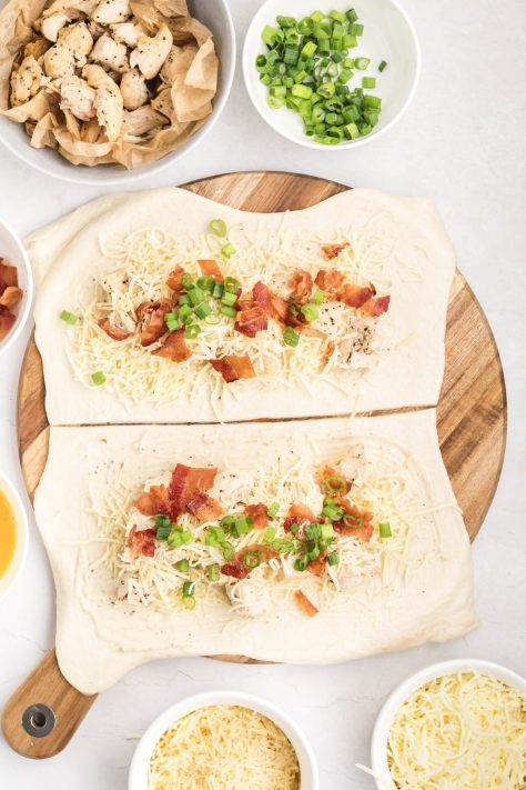 Pizza dough with caesar dressing, chicken, bacon, cheese, and green onions.