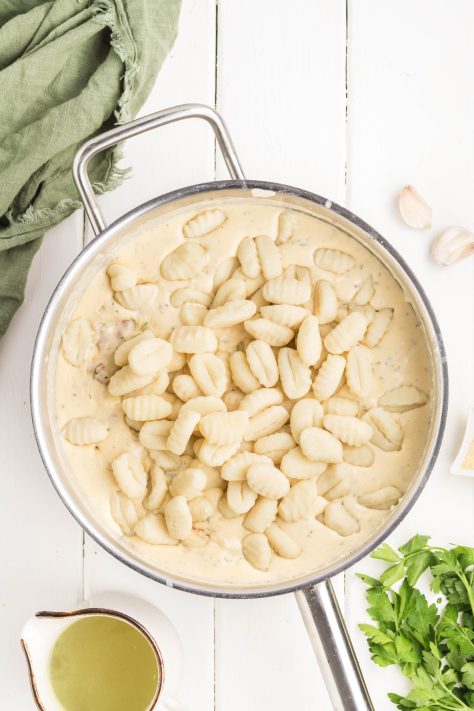 Gnocchi being added to sauce in a skillet.