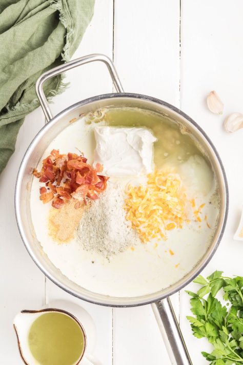 Cream cheese, bacon, and cheeses being added to a sauce.
