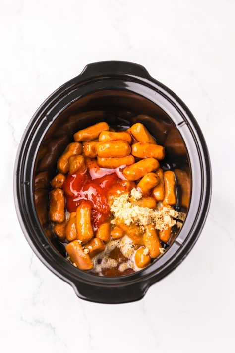 A Crock pot with lit'l smokies, herry cola, sweet chili sauce, brown sugar and ketchup.