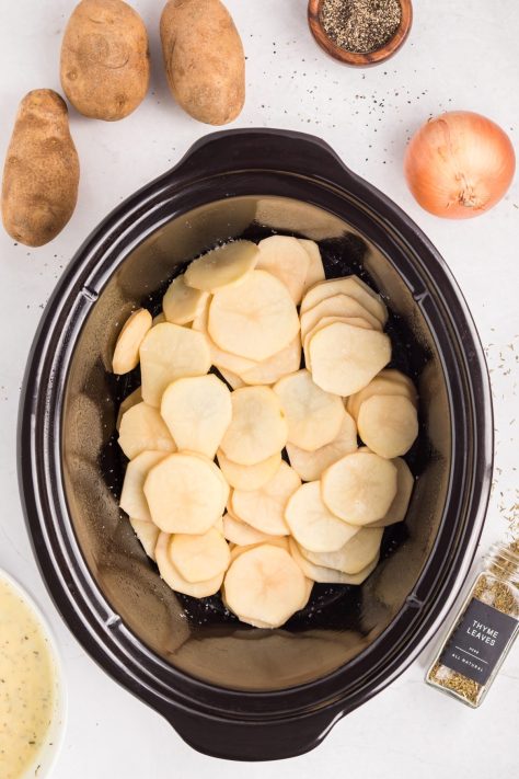 A layer of potatoes on the bottom of a Slow Cooker.