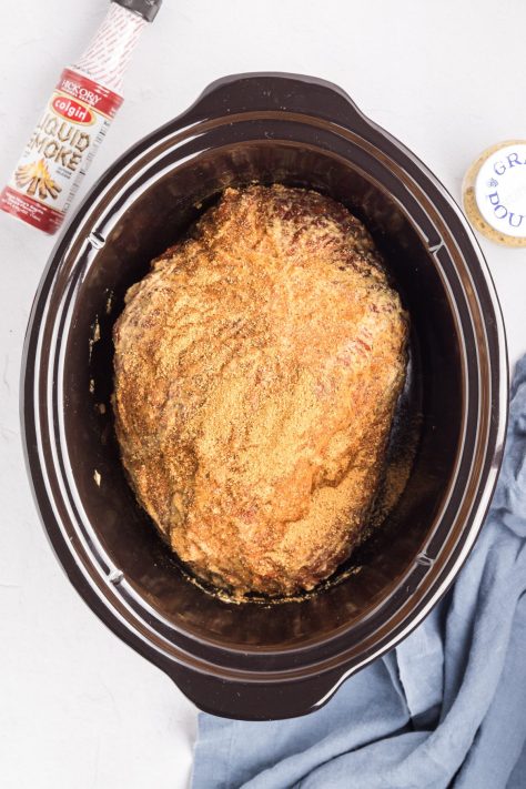 Ham coated in sauce and rub in a Crock pot.