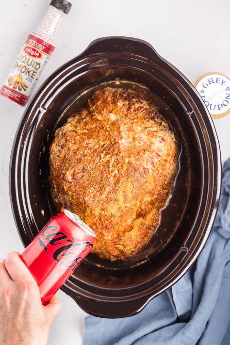Coke being poured over ham in a Slow Cooker.