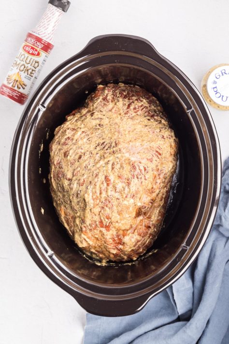 A ham covered in a sauce in a Slow Cooker.