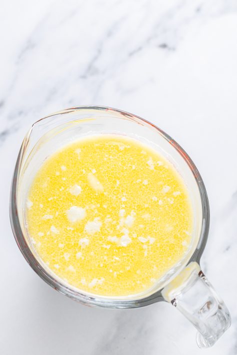 A bowl with melted butter, extract and milk.