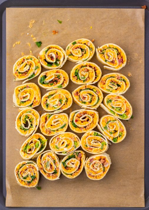 A bunch of cut up Pepper Jelly Pinwheels on a piece of parchment paper.