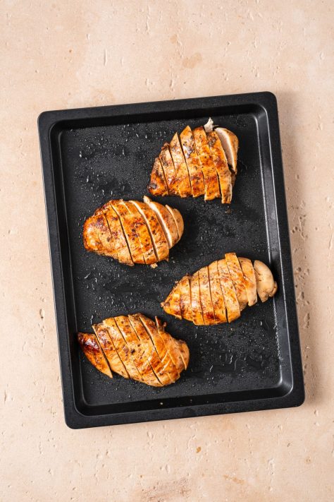 Sliced chicken on a baking sheet.
