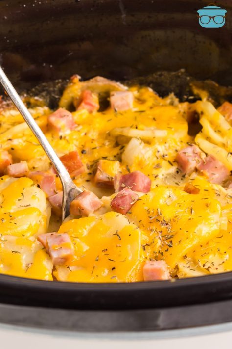 A serving utensil stirring the Crock Pot Ham and Potatoes dish.