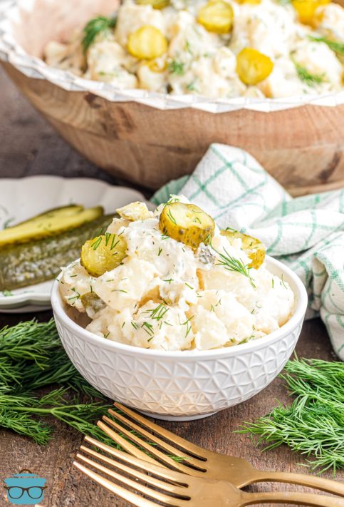 A small white bowl of Dill Pickle Potato Salad.