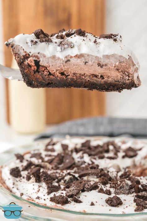 A serving utensil holding a slice of Mud Pie above the rest of the pie.
