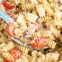 A spoon getting a scoop of Caesar Basil Pasta Salad.