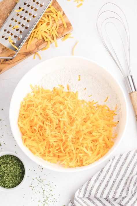 Cheese, flour, sugar, baking powder, and salt in a bowl.