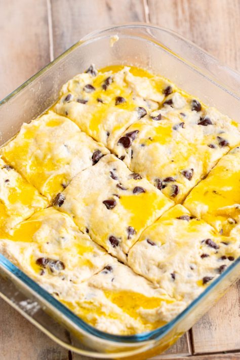 Dough being cut into pieces in a baking dish.