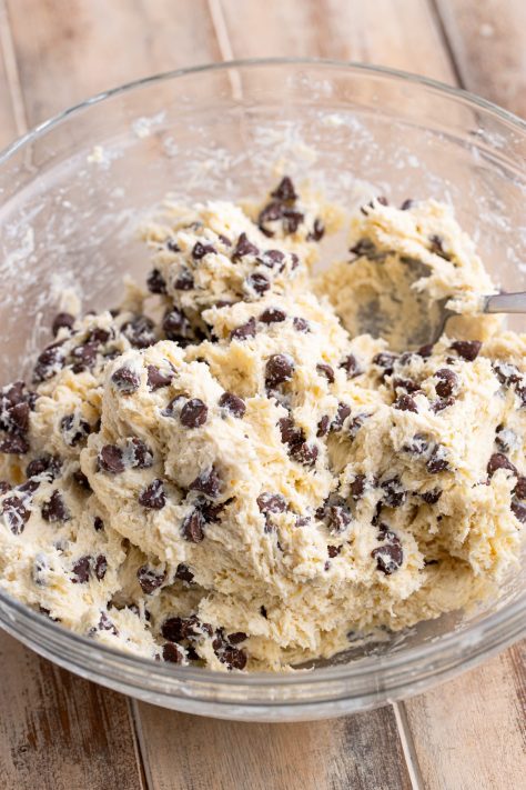 Chocolate chips being mixed in biscuit dough.