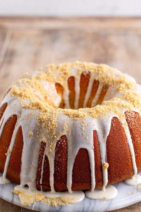 Brown sugar being sprinkled over cake with glaze.