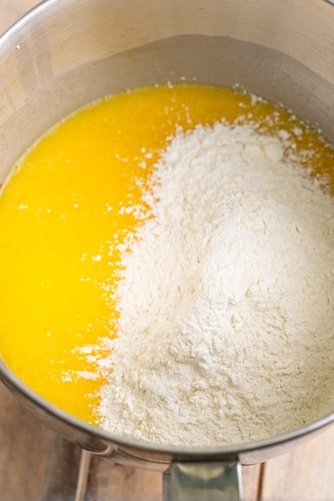 Half the dry mixture being added to the wet ingredient batter in a bowl.