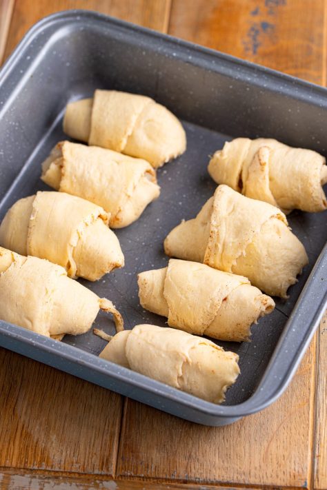 Rolled up unbaked Pear Dumplings in a baking dish.