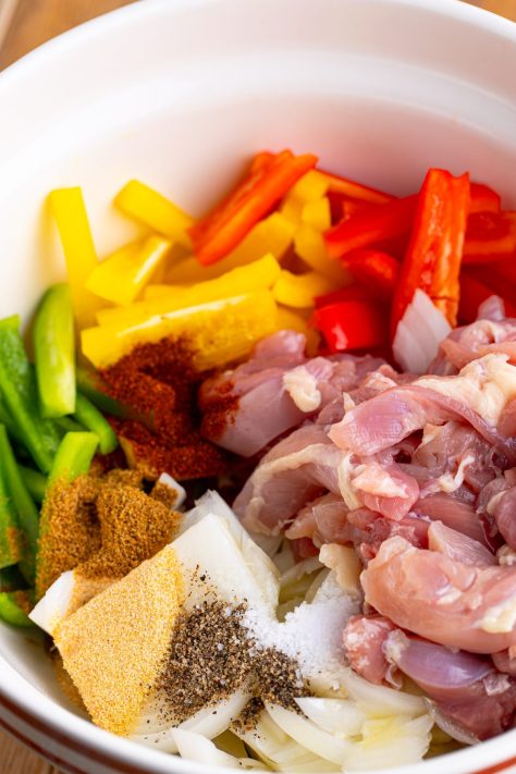 All the ingredients needed for Sheet Pan Chicken Fajitas in a bowl.