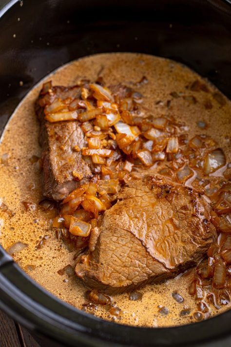 Sauce poured over the onions, gravy and seared steak in a Slow Cooker.