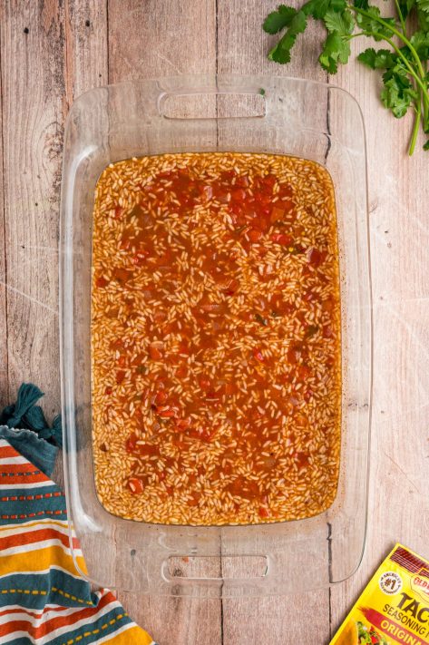 Taco rice with tomatoes and broth in a baking dish.