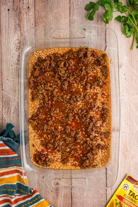 Taco meat in a baking dish with rice and broth.