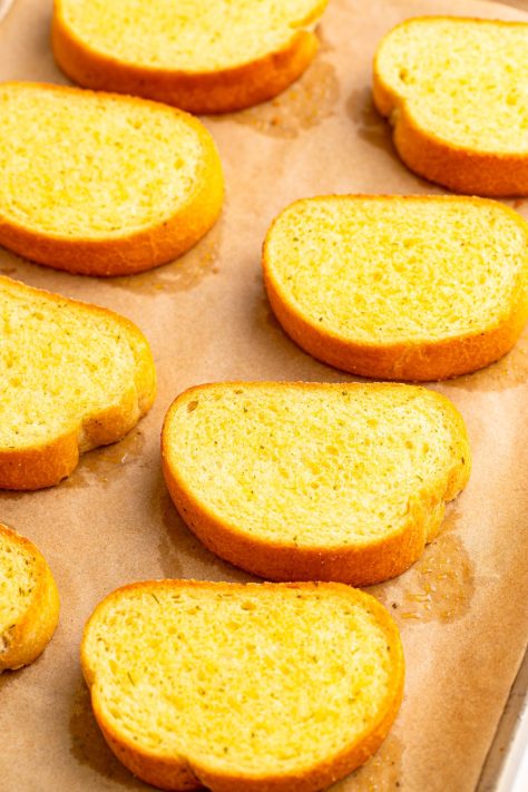 Garlic toast cooking on a lined sheet.