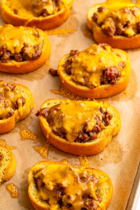 A lined baking sheet with Texas Toast and seasoned meat with melted cheese.