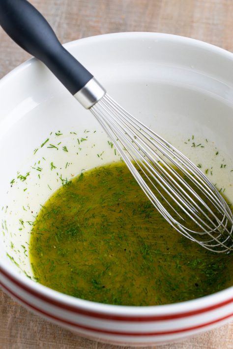 A dill sauce being whisked in a bowl.