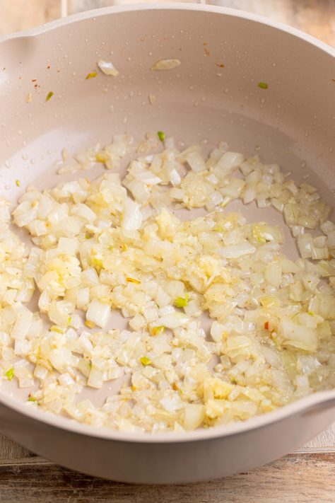 Diced onion being sauteed in a pan.