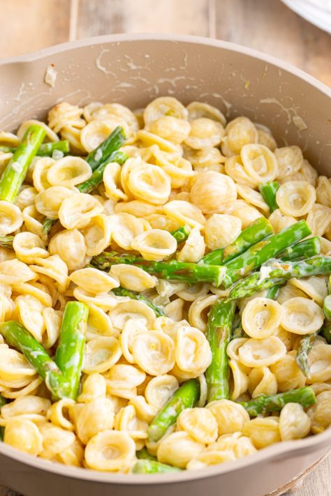 Pasta, sauce and asparagus in a skillet.