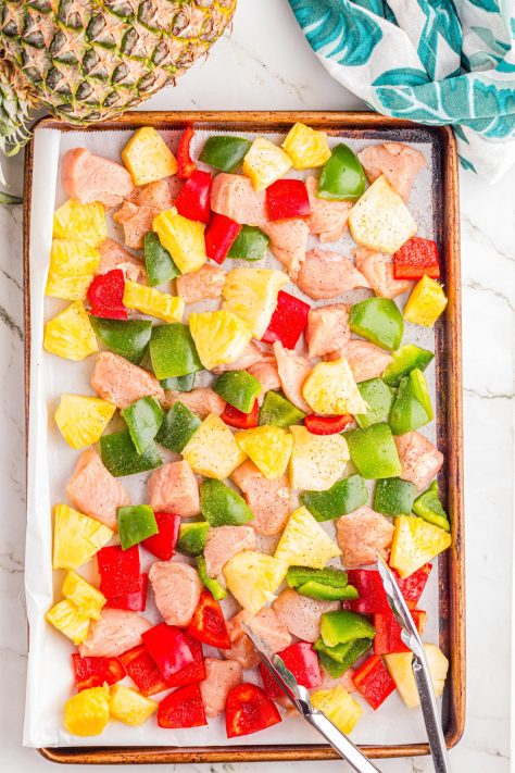 Chicken pieces and bell pepper pieces on a sheet pan.