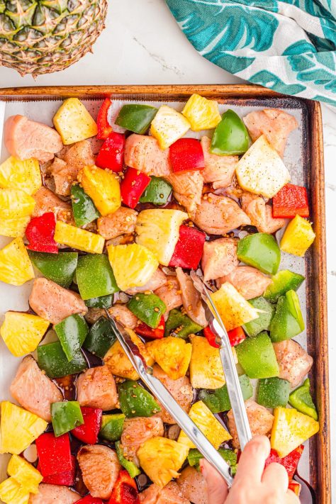 A Hawaiian Chicken Sheet Pan dinner, with tongs flipping things.