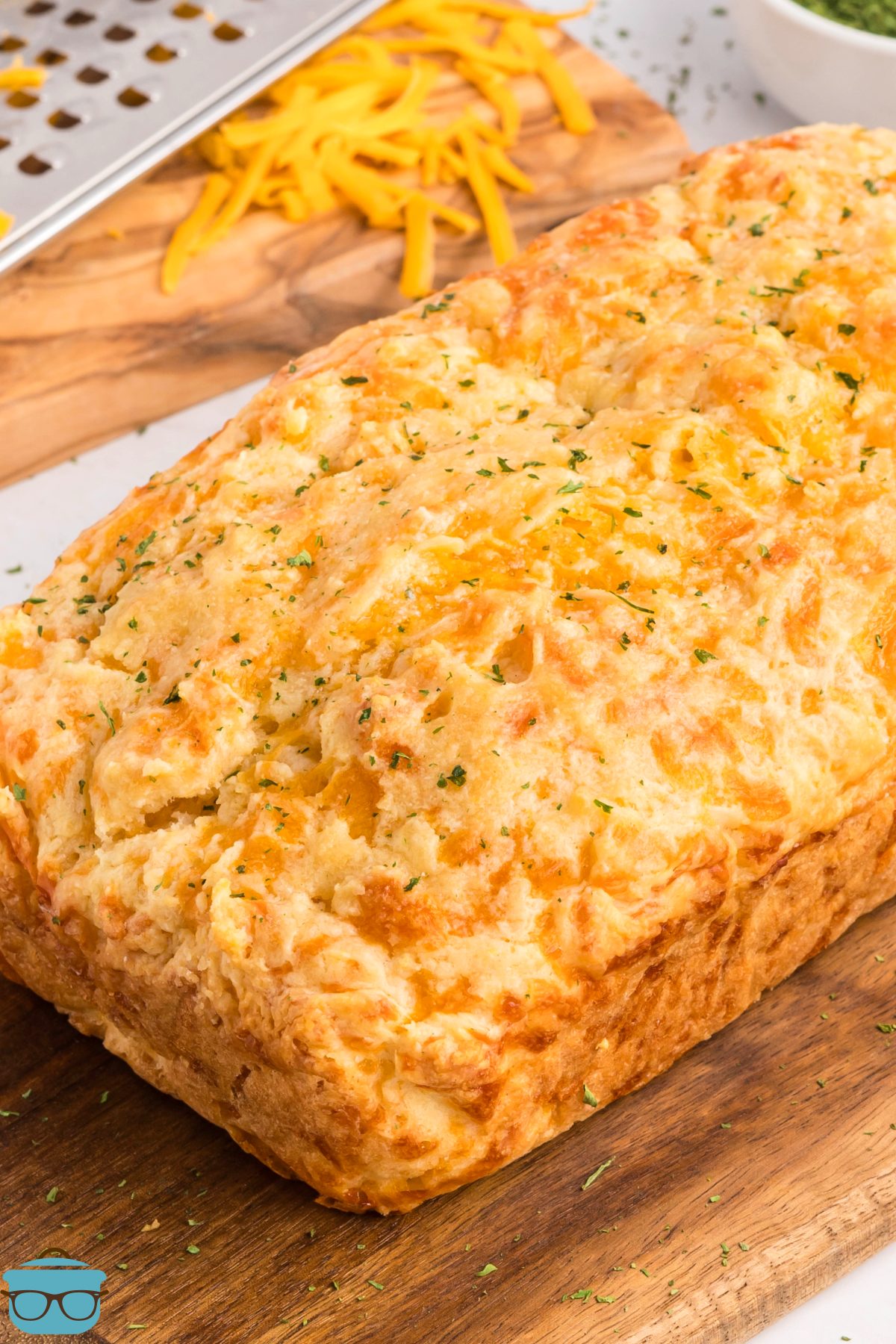 A baked loaf of Cheddar Bay Biscuit Bread on a cutting board. 