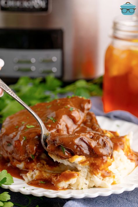A bite of Crock Pot Steak and Gravy on a utensil above the plate of food.