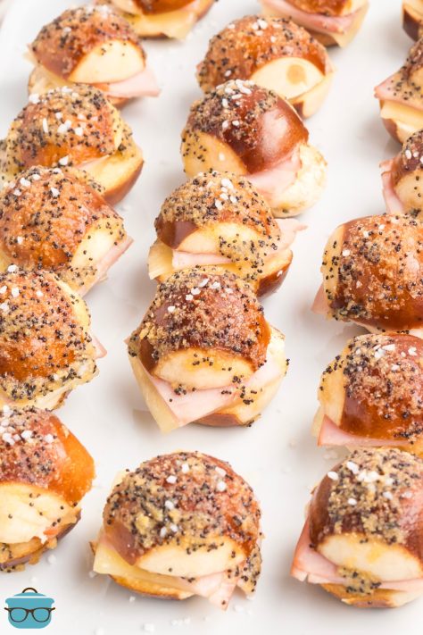 A bunch of Mini Ham and Cheese Pretzel Bites in rows on lined baking tray.