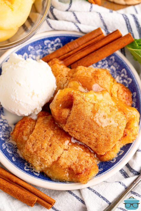 A scoop of ice cream and a few cinnamon sticks with a few Pear Dumplings in a bowl.
