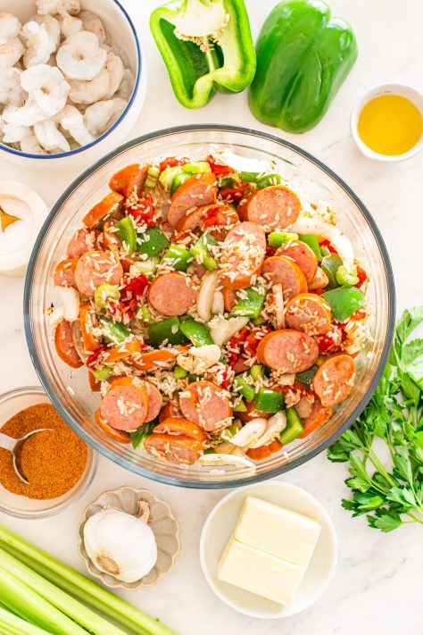 A bowl of sausage, onions, bell peppers, celery, diced tomatoes, garlic, instant rice, broth, olive oil, Cajun seasoning, and salt.